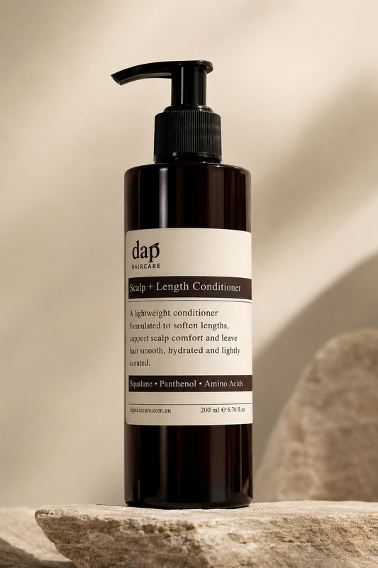 DAP Scalp + Length Conditioner bottle on a stone surface with a neutral background