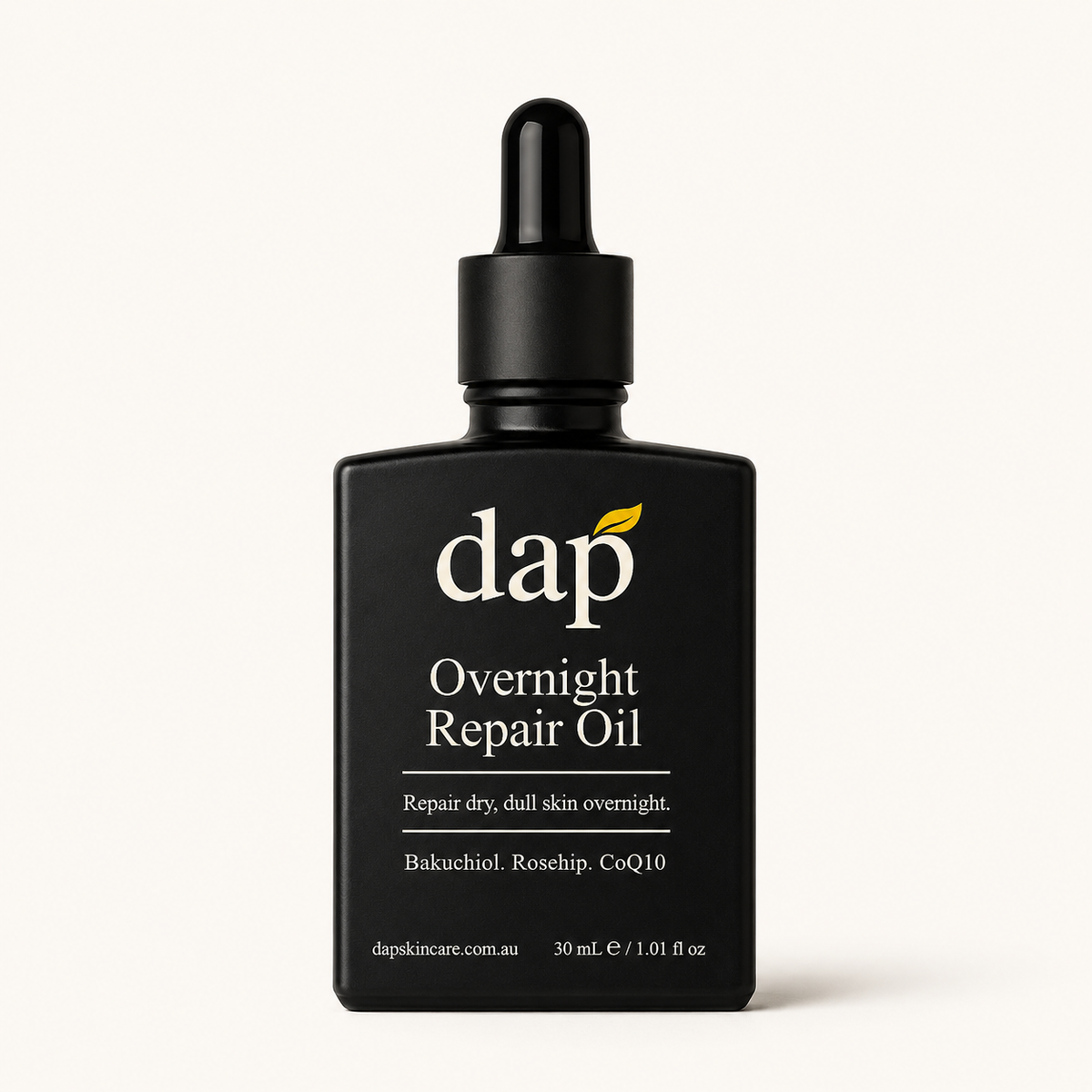 A black dropper bottle of DAP Overnight Repair Oil on a clean, light off-white background. The label features white text and a small yellow leaf accent under the DAP logo.