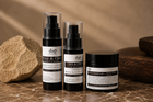 Three DAP Skincare products arranged on a marble surface with a warm neutral background: a Rice & Oats Gel Cleanser pump bottle, a Silk Dropper Face Toner spray bottle, and a Skin Shield Barrier Repair cream jar.